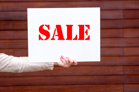a picture of a woman holding a sale sign in his handの写真素材