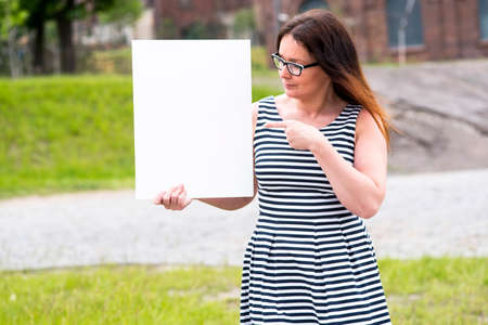 photo of a woman on the outside with an empty white cardの写真素材