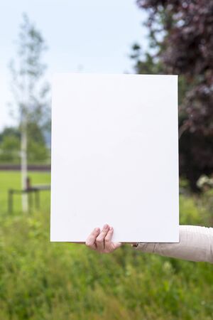 photo of a woman on the outside with an empty white cardの写真素材