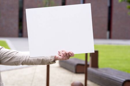 photo of a woman on the outside with an empty white cardの写真素材