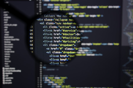 Real Html code developing screen. Programing workflow abstract algorithm concept. Lines of Html code visible under magnifying lens.の写真素材