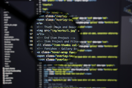 Real Html code developing screen. Programing workflow abstract algorithm concept. Lines of Html code visible under magnifying lens.の写真素材