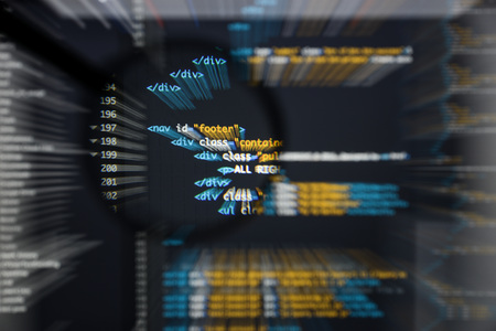 Real Html code developing screen. Programing workflow abstract algorithm concept. Lines of Html code visible under magnifying lens with moviment effect.の写真素材