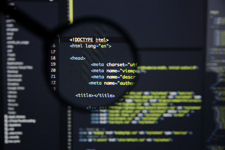 Real Html code developing screen. Programing workflow abstract algorithm concept. Lines of Html code visible under magnifying lens.の写真素材