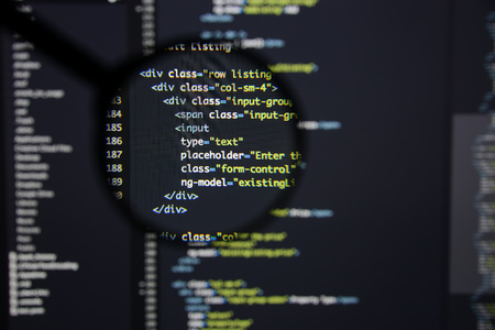 Real Html code developing screen. Programing workflow abstract algorithm concept. Lines of Html code visible under magnifying lens.の写真素材