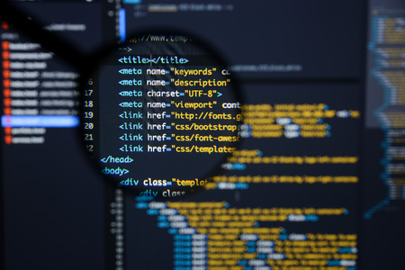 Real Html code developing screen. Programing workflow abstract algorithm concept. Lines of Html code visible under magnifying lens.の写真素材