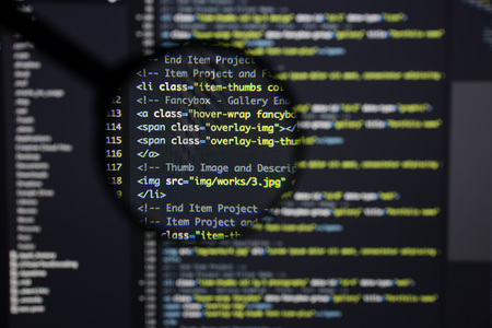 Real Html code developing screen. Programing workflow abstract algorithm concept. Lines of Html code visible under magnifying lens.の写真素材