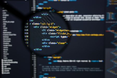 Real Html code developing screen. Programing workflow abstract algorithm concept. Lines of Html code visible under magnifying lens.の写真素材