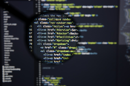 Real Html code developing screen. Programing workflow abstract algorithm concept. Lines of Html code visible under magnifying lens.の写真素材