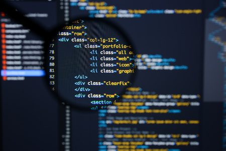 Real Html code developing screen. Programing workflow abstract algorithm concept. Lines of Html code visible under magnifying lens.の写真素材