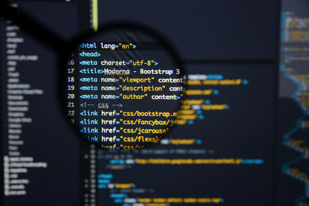 Real Html code developing screen. Programing workflow abstract algorithm concept. Lines of Html code visible under magnifying lens.の写真素材
