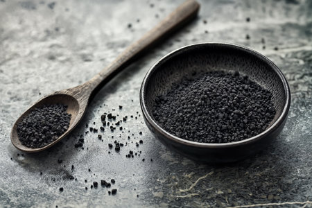 Granular activated carbon in a ceramic bowl and wooden spoon, perfect for commercial, health, and environmental product conceptsの素材