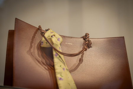 Milan, Italy - 2026, 3 Feb: Jil Sander FW25 brown leather handbag with braided handles and floral...