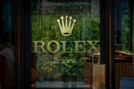 Milan, Italy - 2026, 3 Feb: Elegant Rolex storefront with gold logo, lush green wall, and modern...