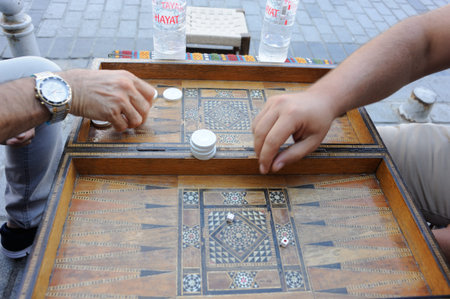 Men playing backgammon board game with an old wooden table, checkers and dice in Turkey