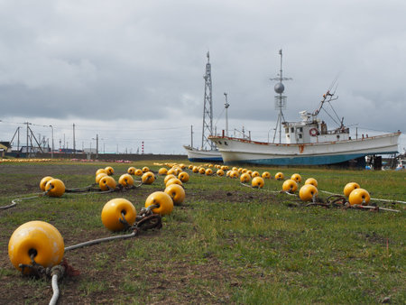 Yellow buoys and beacons on seaside harbour in fishing village on cloudy day on Hokkaido island,...