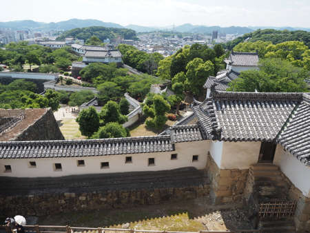 Ancient samurai castle in Himeji city in Japan with white walls, dark tile roofs and stone walls on a sunny day in summer with blue sky and white cloudsのeditorial素材