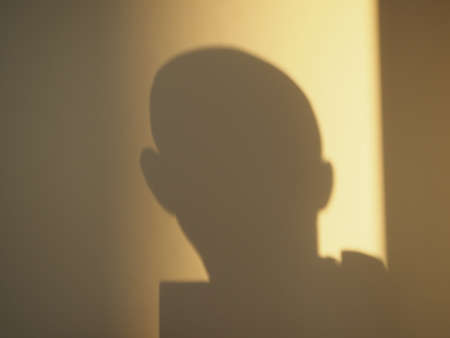 Self-portrait on the wall - a silhouette of a man cast on a wall by a yellow sunlightの写真素材