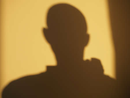 Self-portrait on the wall - a silhouette of a man cast on a wall by a yellow sunlightの写真素材