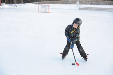 A young ice hockey amateur player on ice rink playing hockey with a stick in winter in Sweden