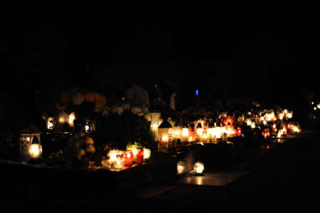 Candle lights on graves and tombstones in cemetery at night in Poland on All Saints 'Day or All Souls' Day or Halloween or Zaduszki or Day of the Deadの写真素材