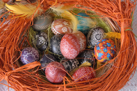A traditional dyed colourful Easter egg in a basket with feathers in Poland called pisanka or...