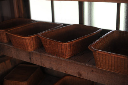 Rattan woven wicker baskets or caskets on a shelve in dark room