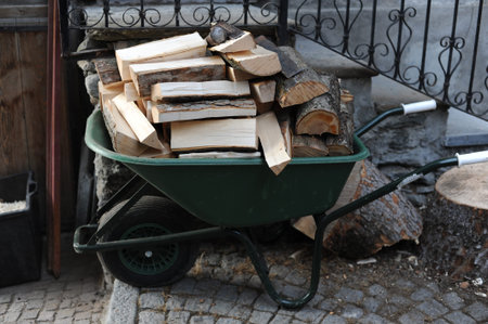 A wheelbarrow full of chopped timber firewood with handles and a wheel