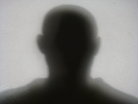Dark silhouette of a man or woman head on a white wall. Shadow. Shade. Light.