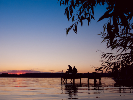 Canoe trail of the Krutynia River. Two men fishing in the lake during a beautiful sunset. Lake Zyzdroj, Wariman-Masurian province, Poland, Europe.の写真素材