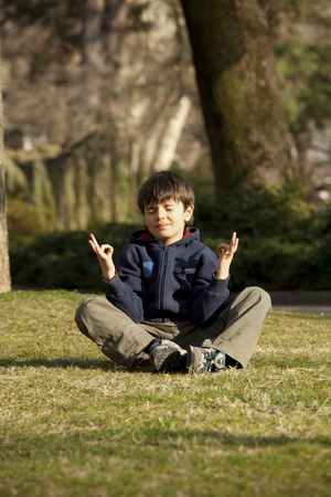 child in meditation, yoga pose in a parkの写真素材