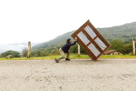 Man carries wardrobe along a mountain road