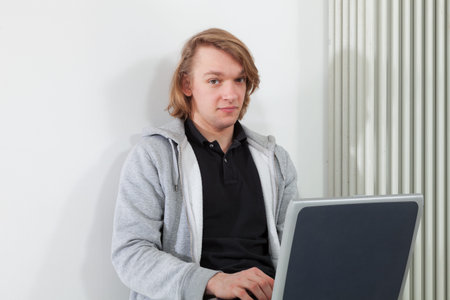 guy sitting with laptop near the radiator, studio portrait 