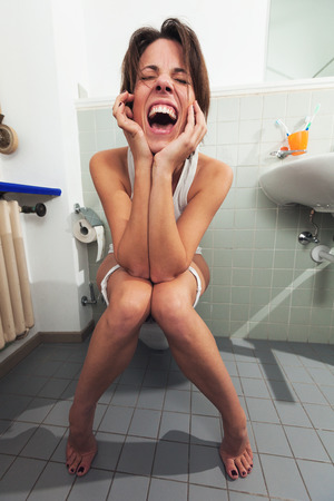 screaming woman sitting on the toiletの写真素材