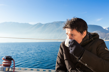 woman makes a coffee break aboard his sailboatの写真素材