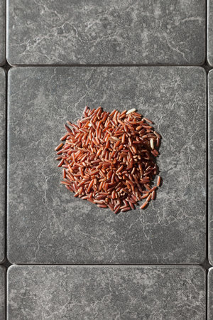 Pile of red rice on gray tiles