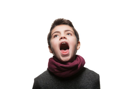 Teenage boy sings in the studio, open mouth, isolated on whiteの写真素材