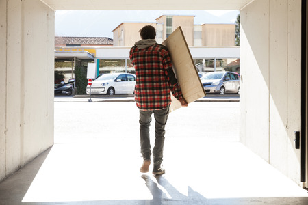 Guy goes out with a wooden plank, rear viewの写真素材