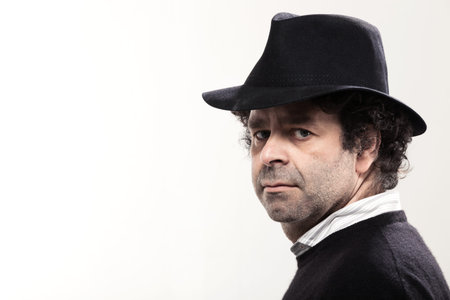 Closeup of a man with a black hat, looking at camera