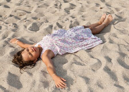 portrait of a little girl lying on the beachの写真素材