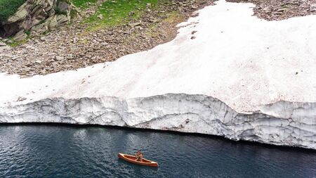 Boy in a wooden canoe on a Swiss mountain lakeの写真素材
