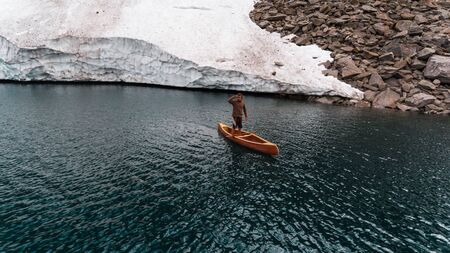 Boy in a wooden canoe on a Swiss mountain lakeの写真素材
