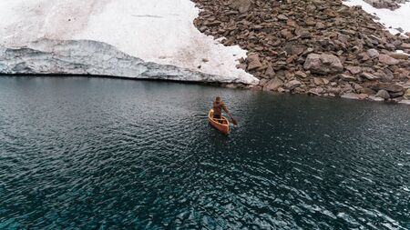 Boy in a wooden canoe on a Swiss mountain lakeの写真素材