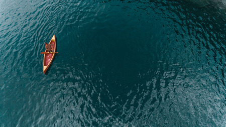 Boy in a wooden canoe on a Swiss mountain lakeの写真素材