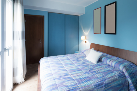 Blue bedroom with frames on the wall. Nobody insideの写真素材