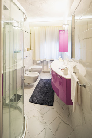 Modern bathroom with fuchsia furniture and white tiles. Nobody insideの写真素材