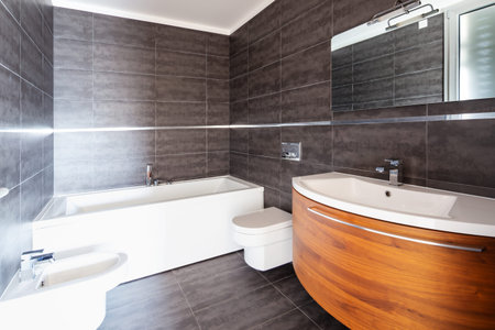 Modern bathroom with gray marble tiles and wooden sink. Nobody inside