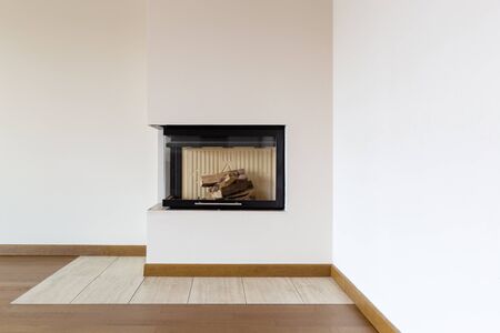Detail of fireplace with wooden logs and white wall. Close upの写真素材