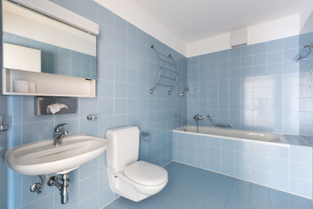 Bathroom with vintage blue tiles. Sink and toilet. Nobody inside.