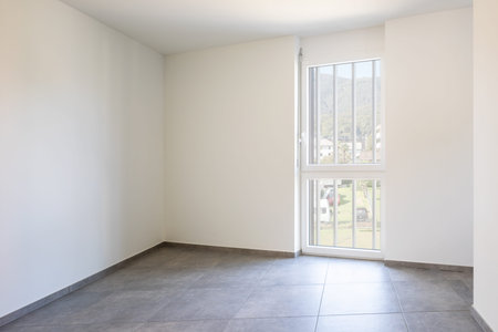 Empty room with white walls and bright window. Nobody inside
